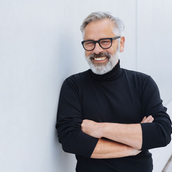 middle aged man smiling against wall